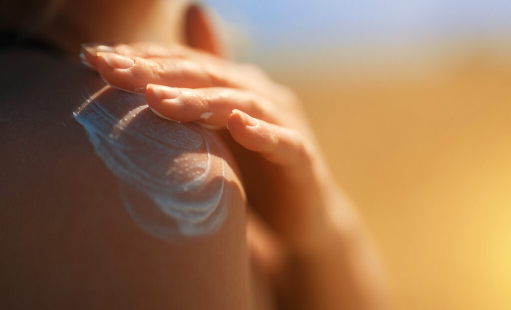 Photo of a woman rubbing sunscreen on her shoulder