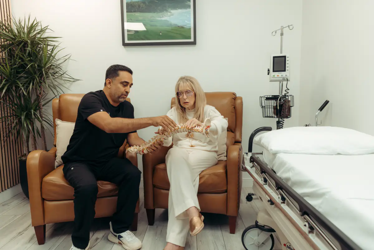 A physician walking a patient through a spine model in a consultation room.