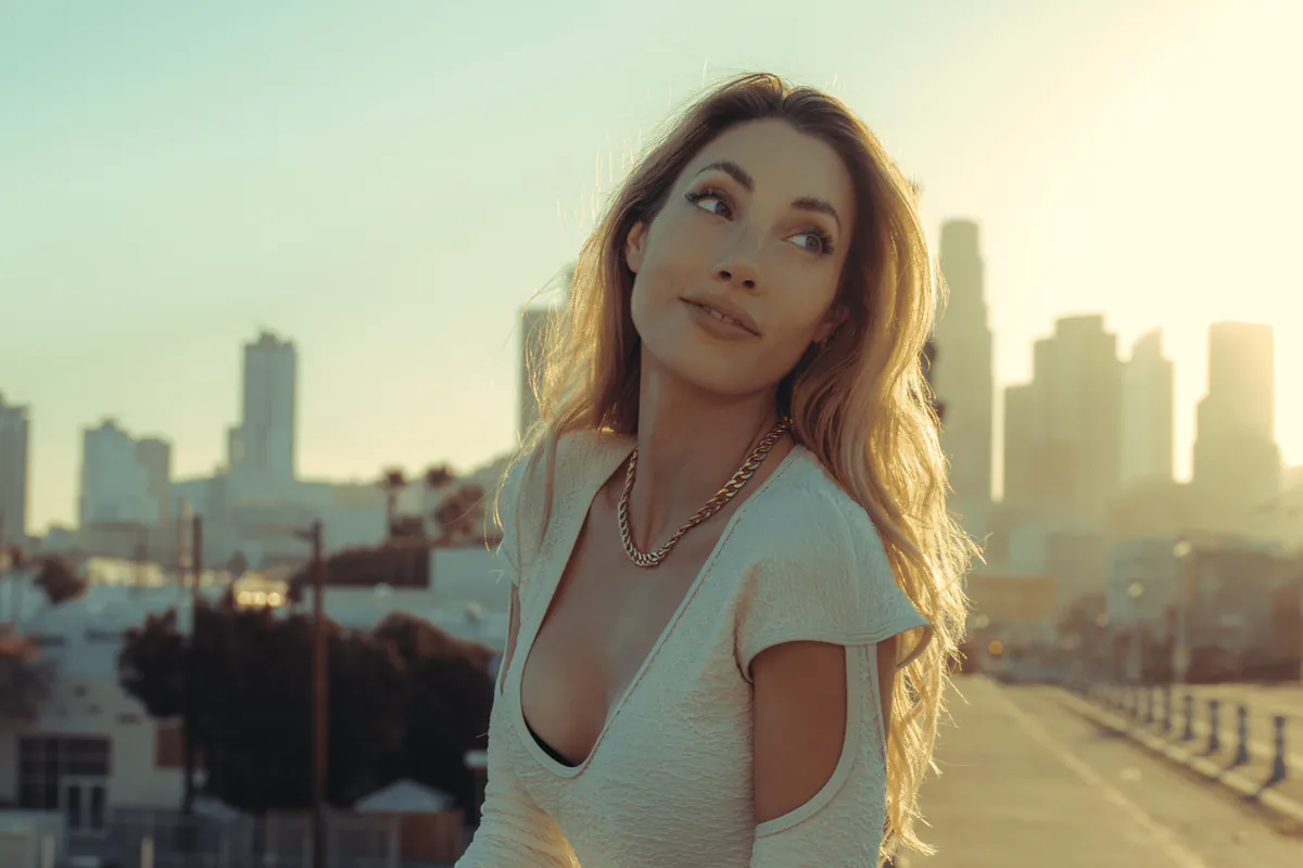 A woman at a bridge rail at sunset, the skyline behind her, from our Reveal Lasers campaign.